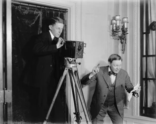 Twee mannen gebruiken een filmcamera binnenshuis, ca. 1908-20